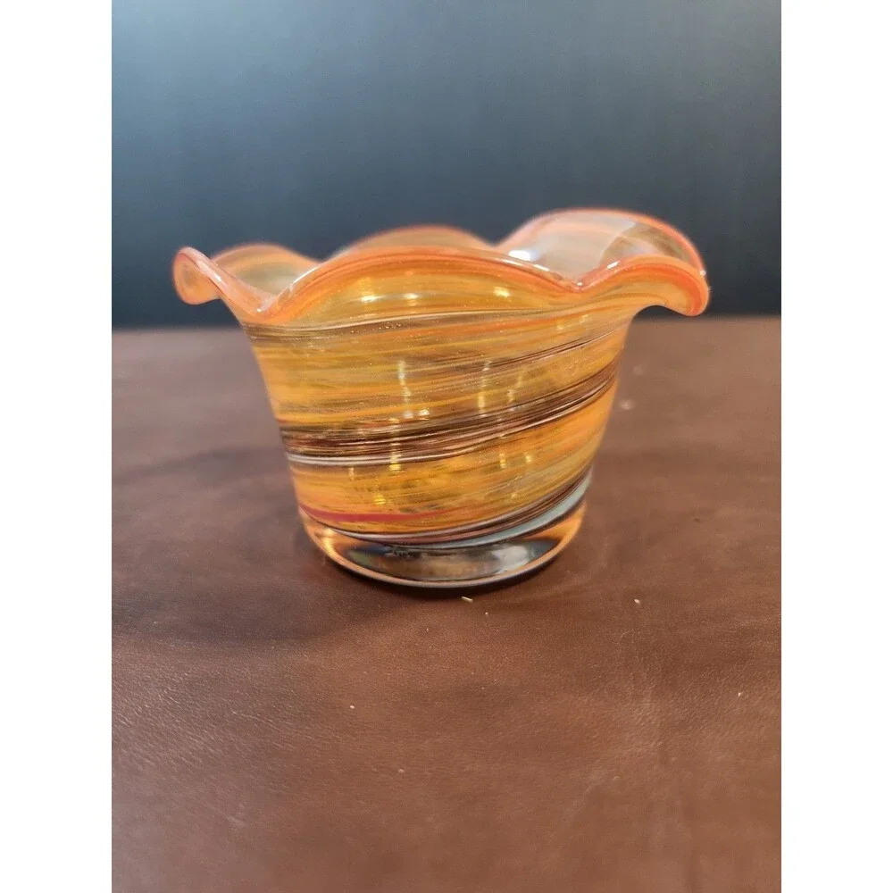 hand-blown art glass bowl features a vibrant orange and amber swirl pattern with
